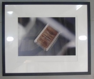 Framed photograph showing an artistically blurred close-up of the 'Handbuilt in England' badge on Aston Martin cars
