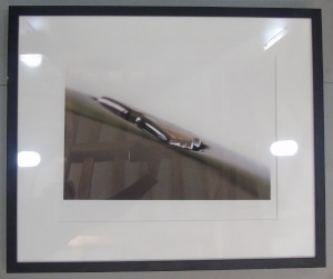 Framed photograph showing a close up of an enamel Aston Martin 'wings' badge